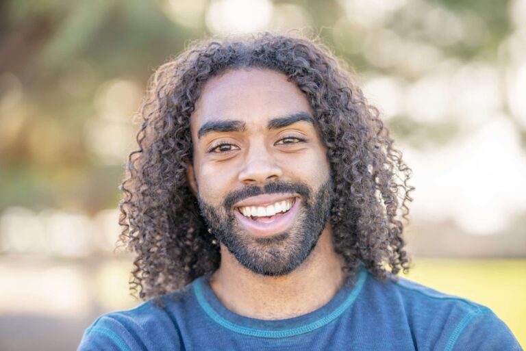 A handsome young male adult of African descent is smiling at the camera.