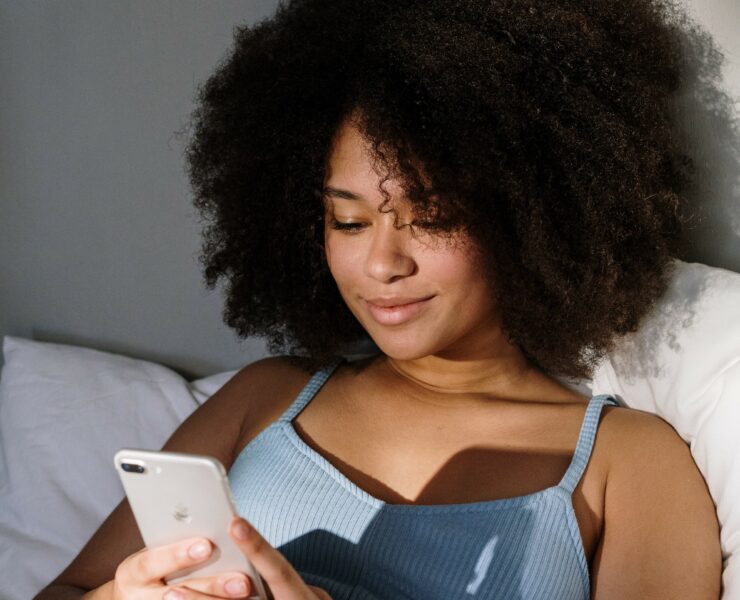 woman in bed looking at her phone
