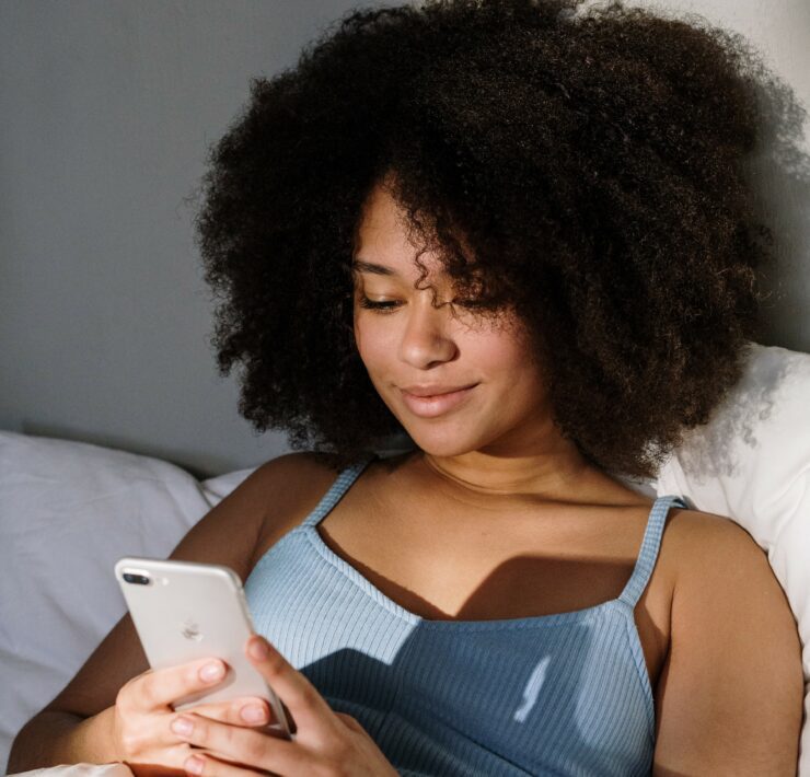 woman in bed looking at her phone
