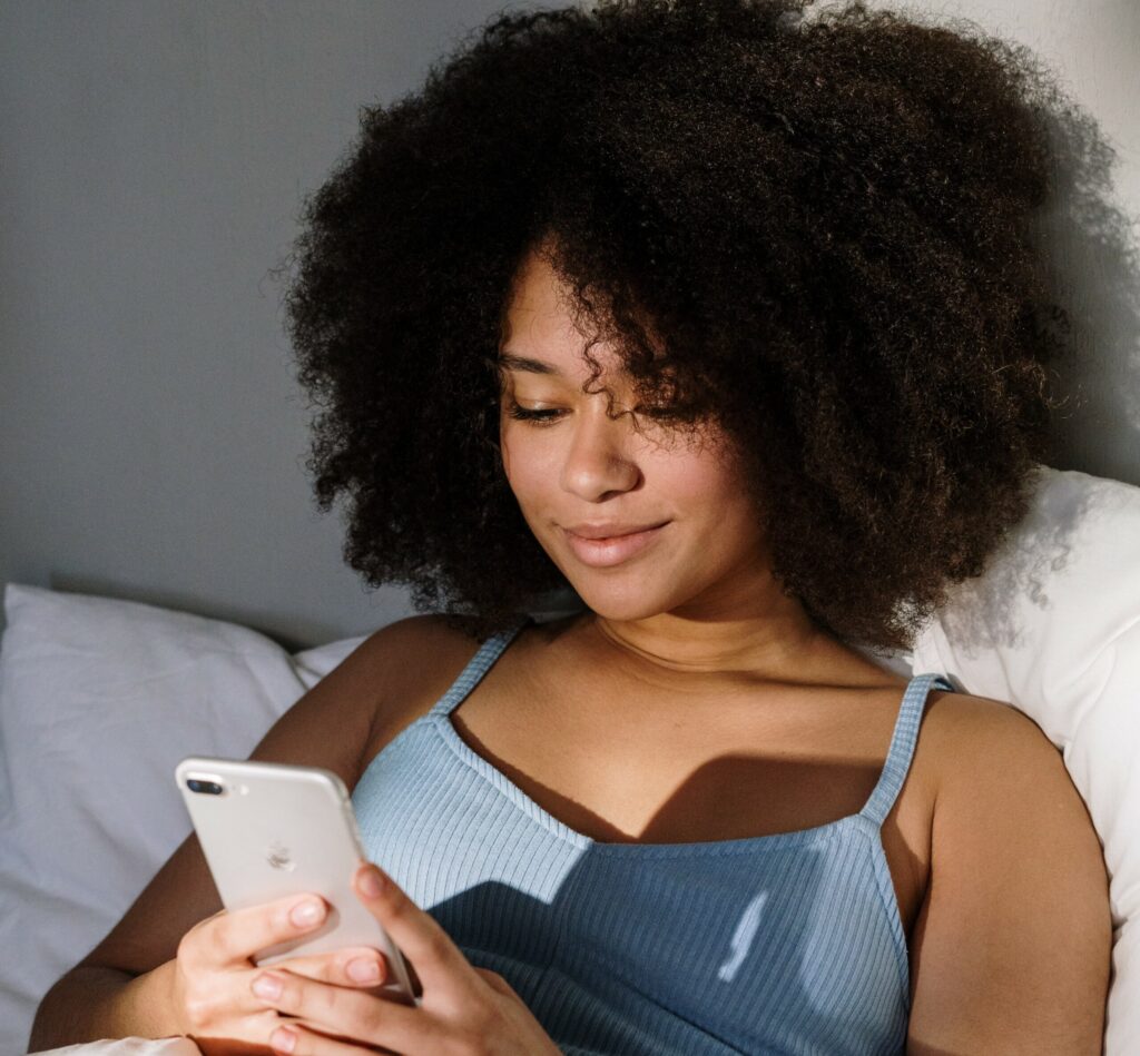 woman in bed looking at her phone