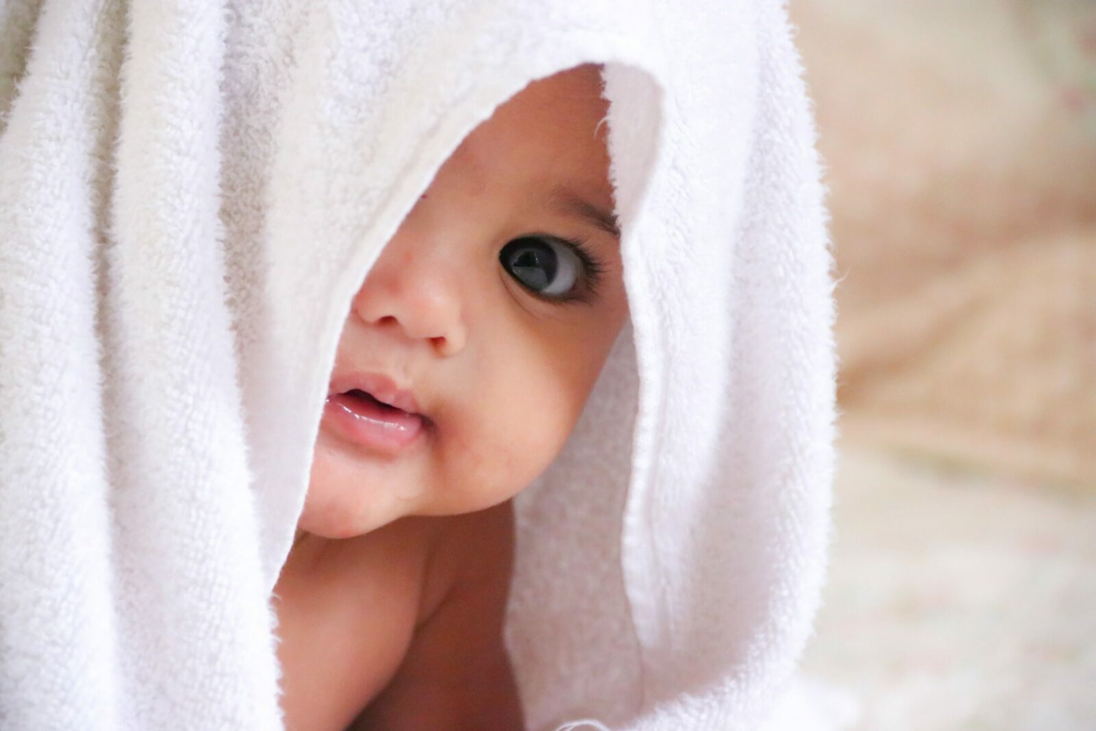 baby peeking out from a white towel