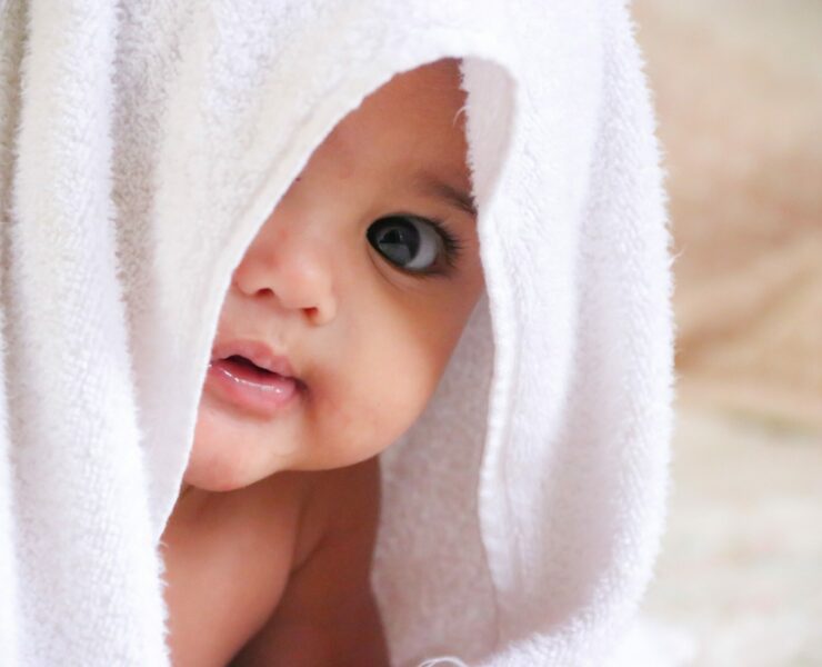 baby peeking out from a white towel