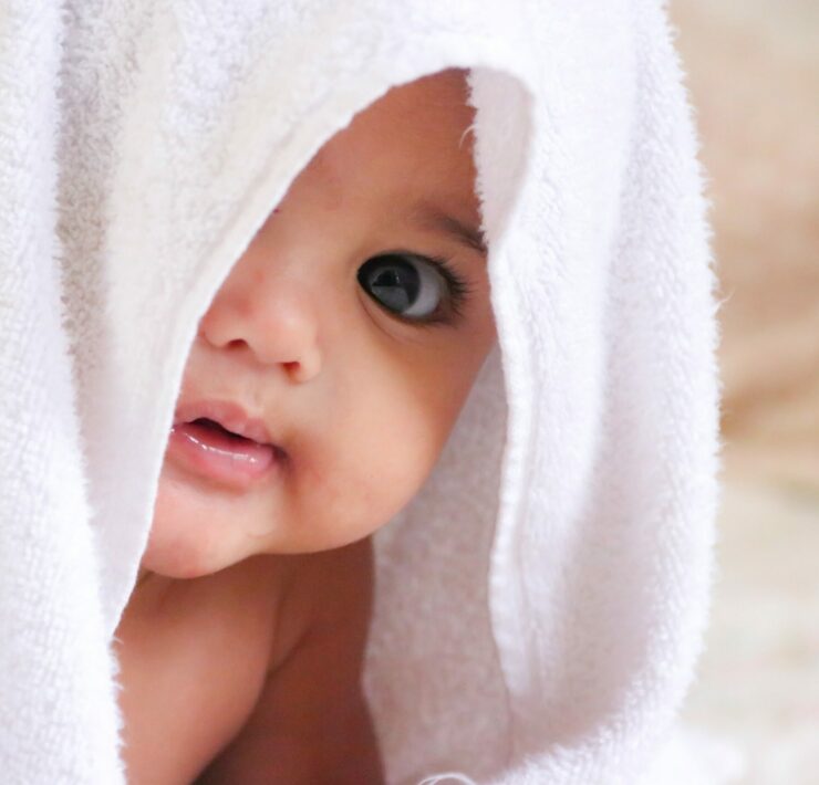 baby peeking out from a white towel