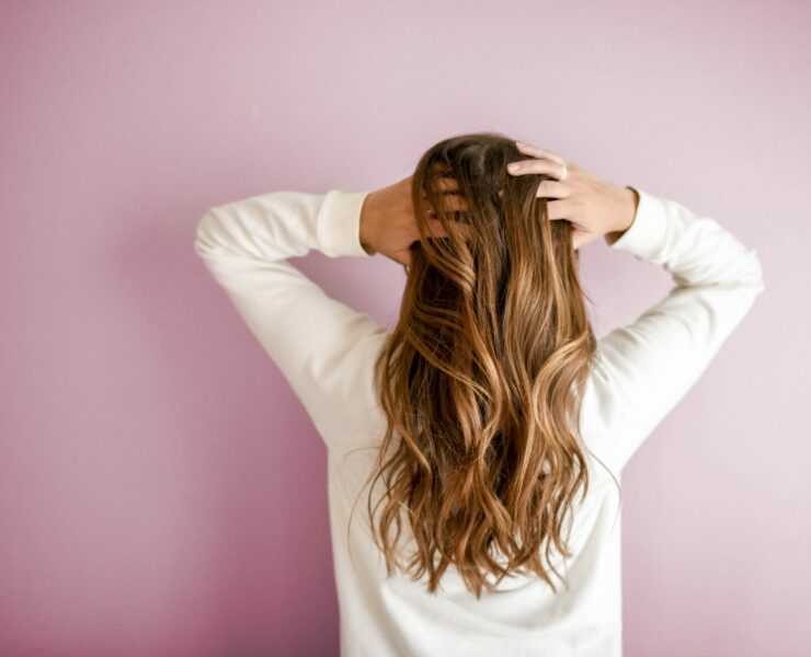 back of woman with hands in her long hair