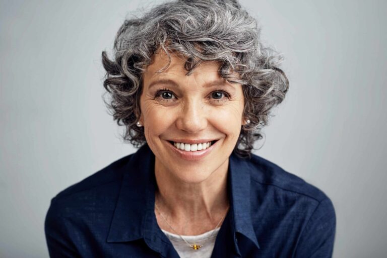happy mature woman posing against a gray background