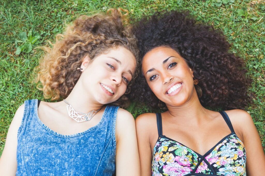 a multiracial couple of women lying on the grass