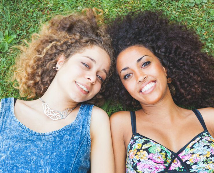 a multiracial couple of women lying on the grass