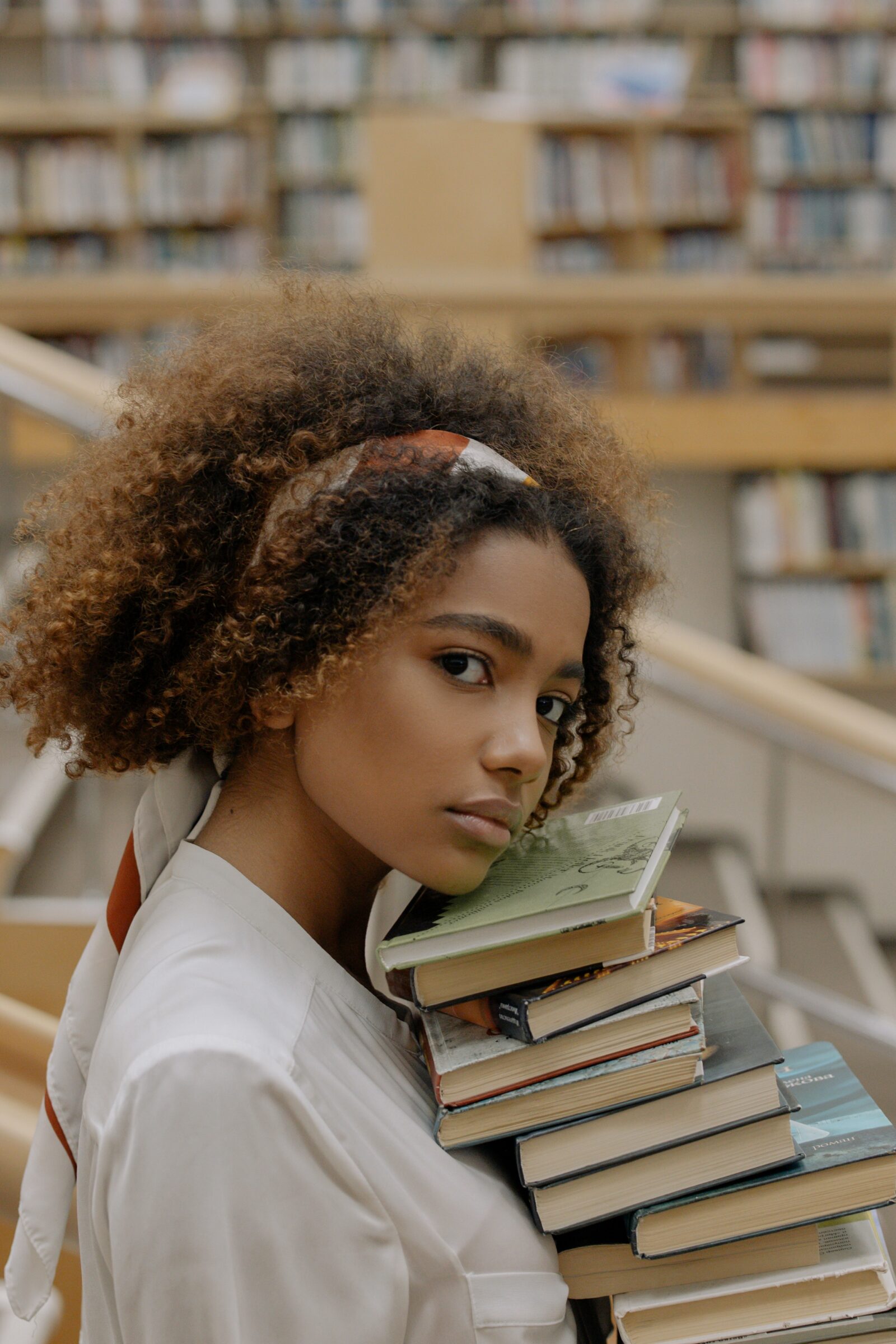 young woman with curly hair holding a stack of books