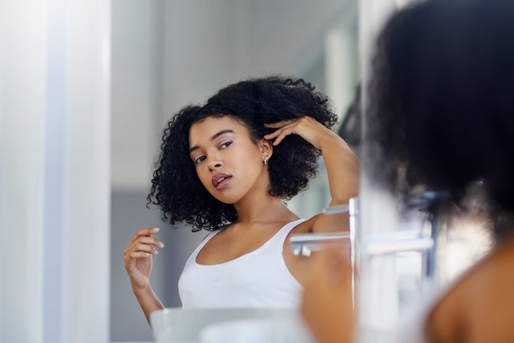 beautiful young woman styling her hair in her bathroom