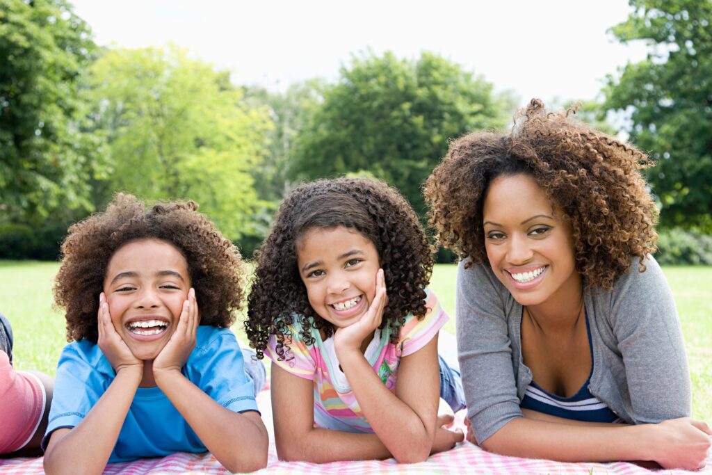 mother and children laying on blanket in the park