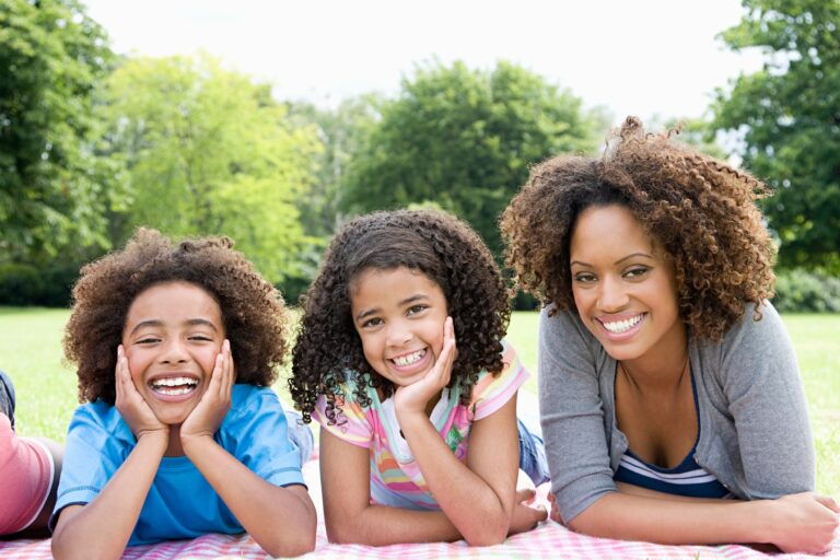 mother and children laying on blanket in the park